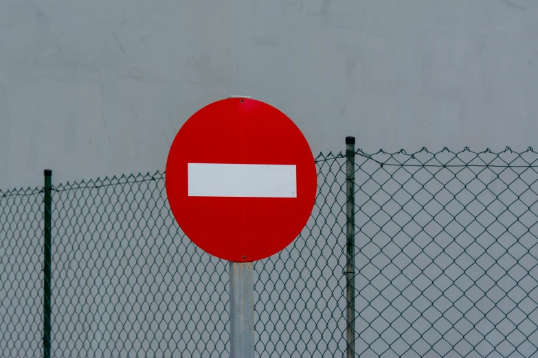 a red and white sign next to a chain link fence