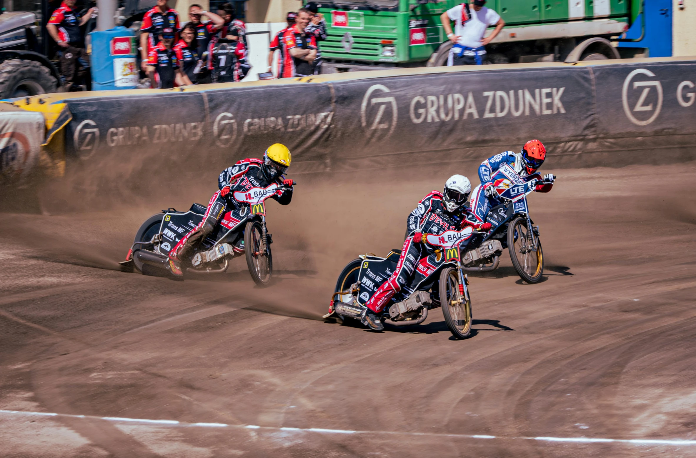 three dirt bike racers racing on a track in front of spectators