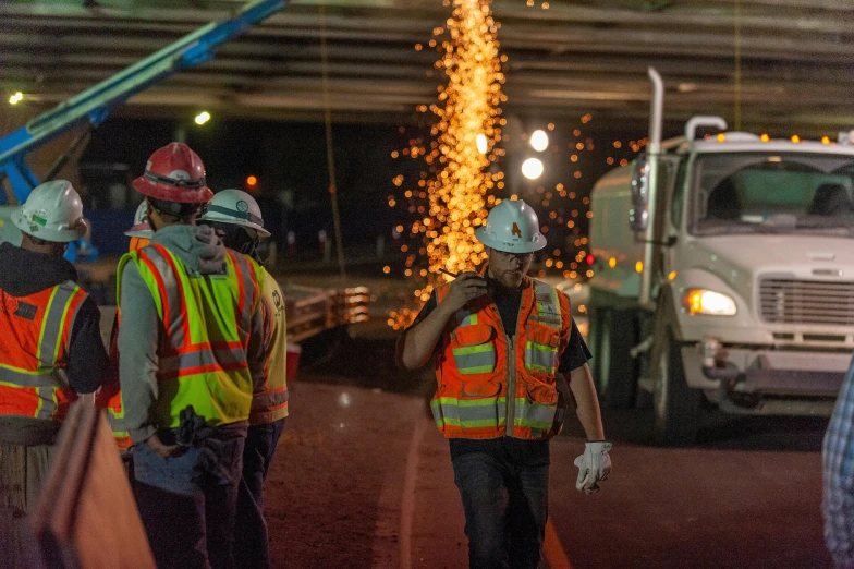 three men wearing safety gear, standing near cars