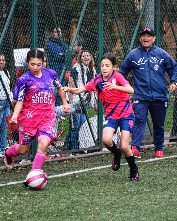 a couple of young women kicking around a soccer ball