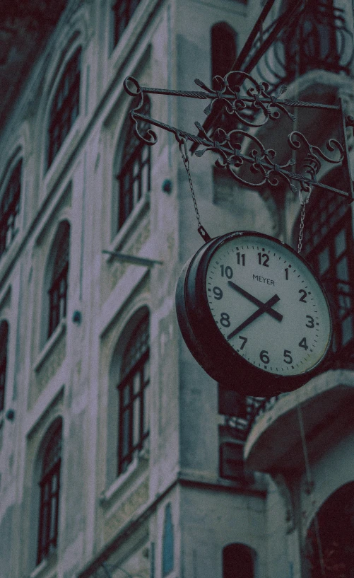 an old clock hangs from the side of a building