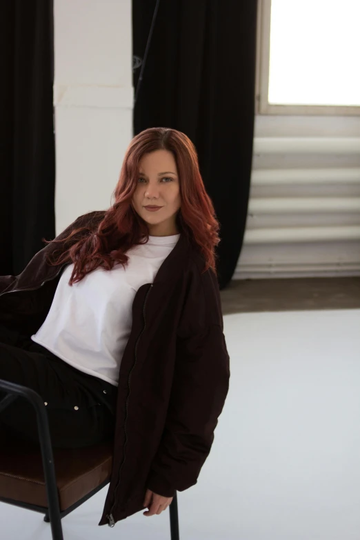 a woman wearing a jacket sitting in a chair