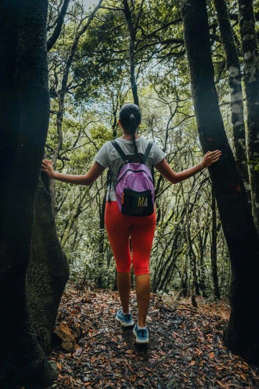 a woman with a backpack walks up a trail in the woods