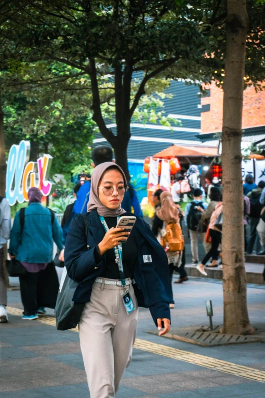 a woman walking down a street looking at her cell phone
