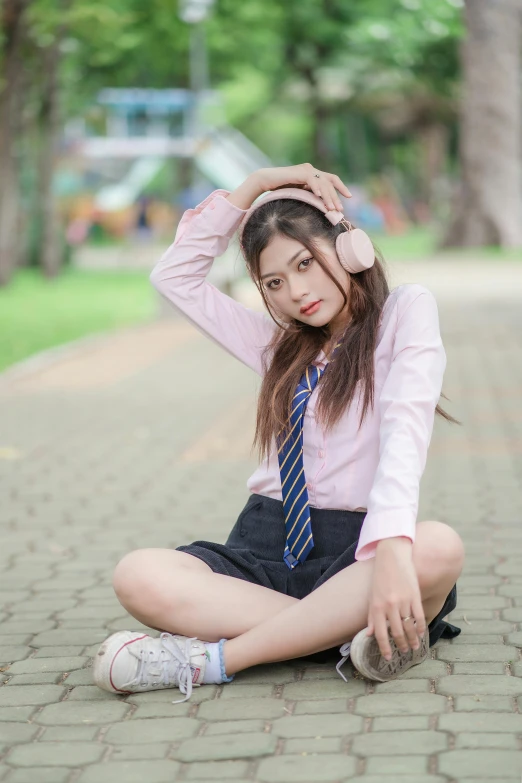 a young woman in a skirt sitting on a brick ground