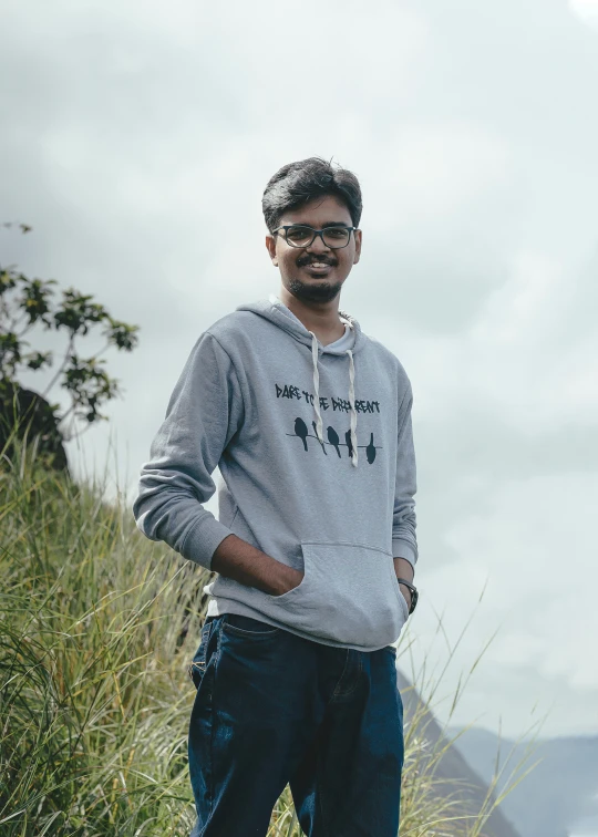 a man stands in tall grass while posing for the camera