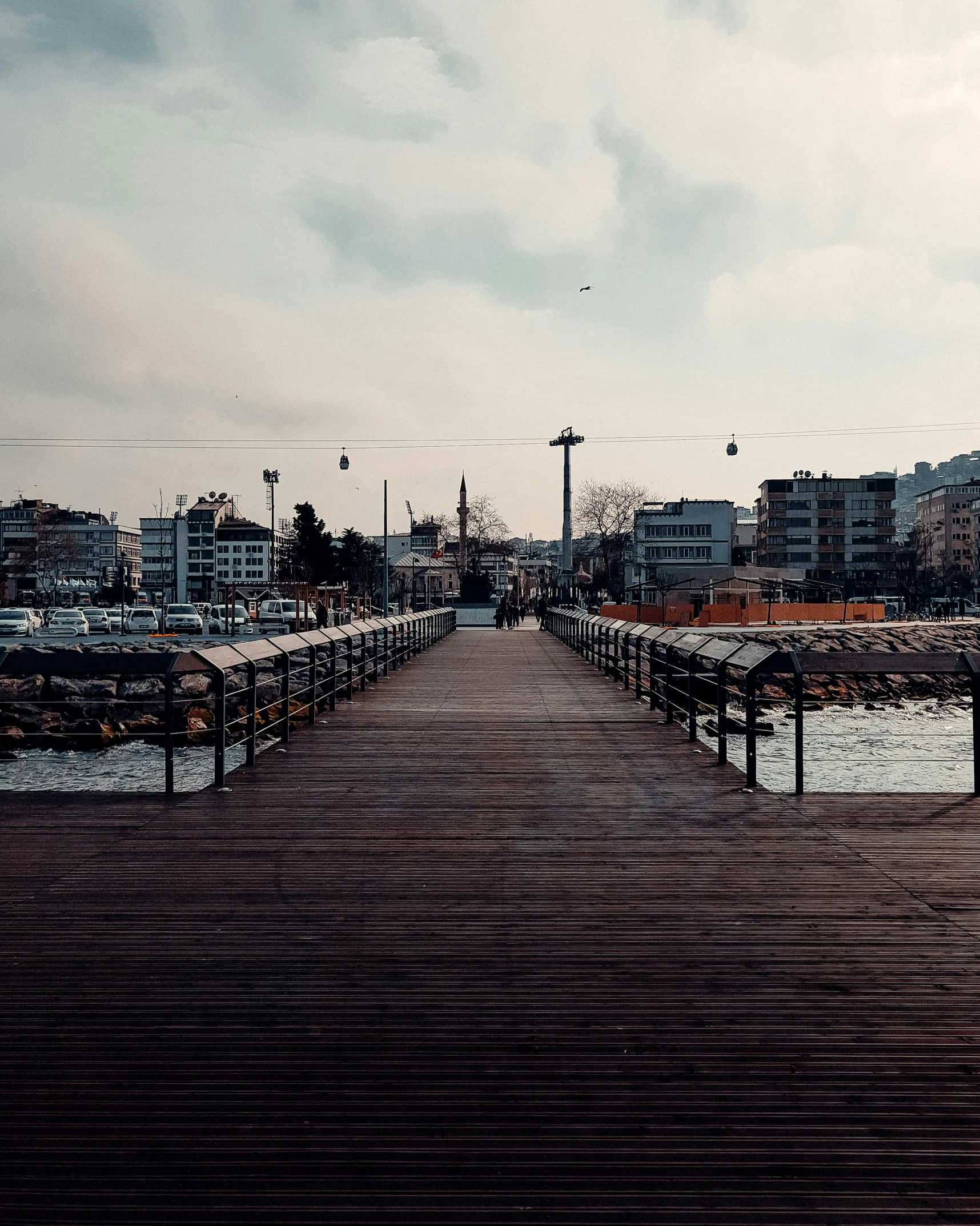 a small wooden pier near the ocean in front of some buildings