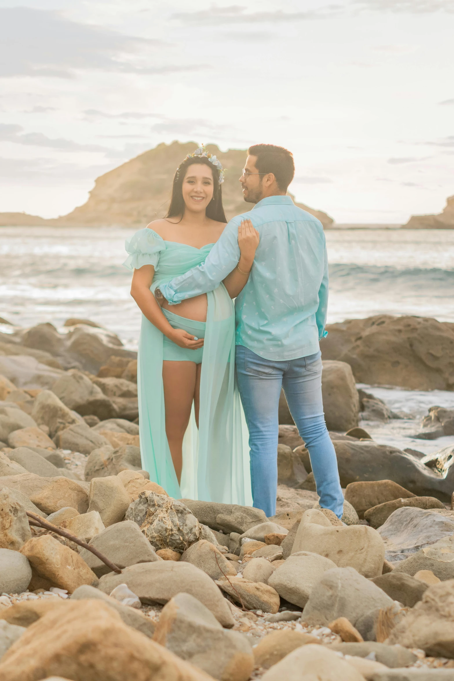 man and woman pose on beach in dresses