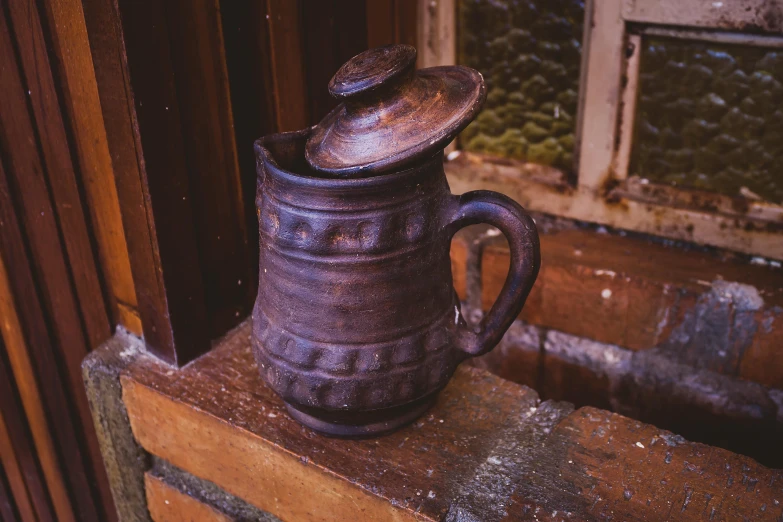 a mug with an open lid sits on a window sill