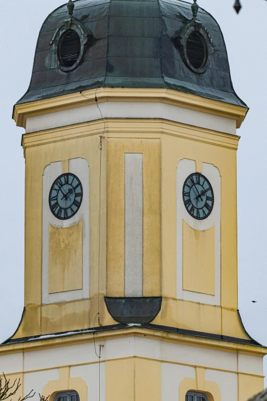 a large yellow tower with two clocks on each of it's sides