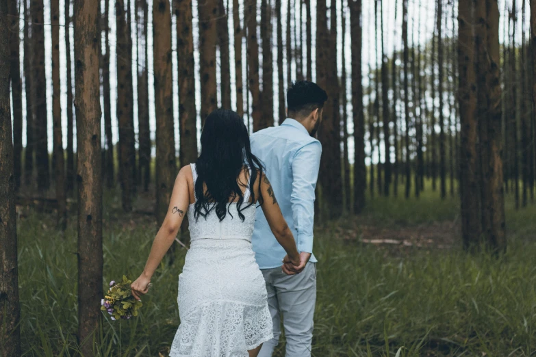 the bride and groom stand in front of an array of trees