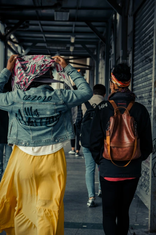 two people walk down a street near a graffiti - covered wall