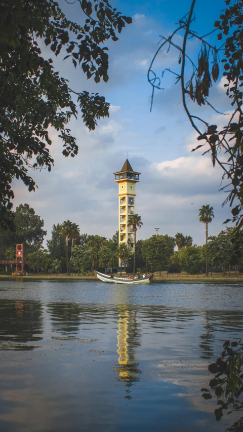 a beautiful tower stands on the horizon of a small lake