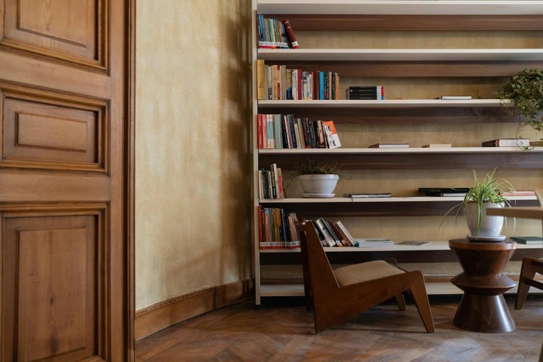 a bookshelf with several open shelves, vase, potted plant and two chairs