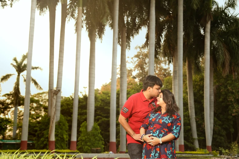 a beautiful couple emcing each other by the palm trees