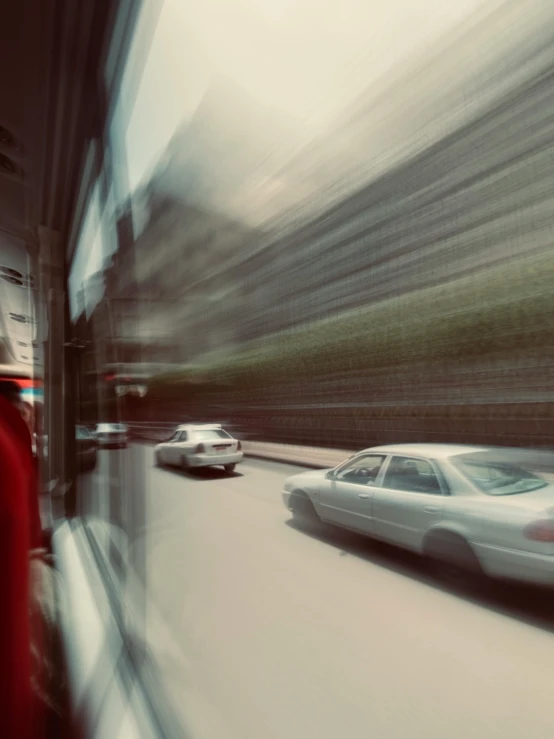 a couple of cars traveling down a street past a tall building