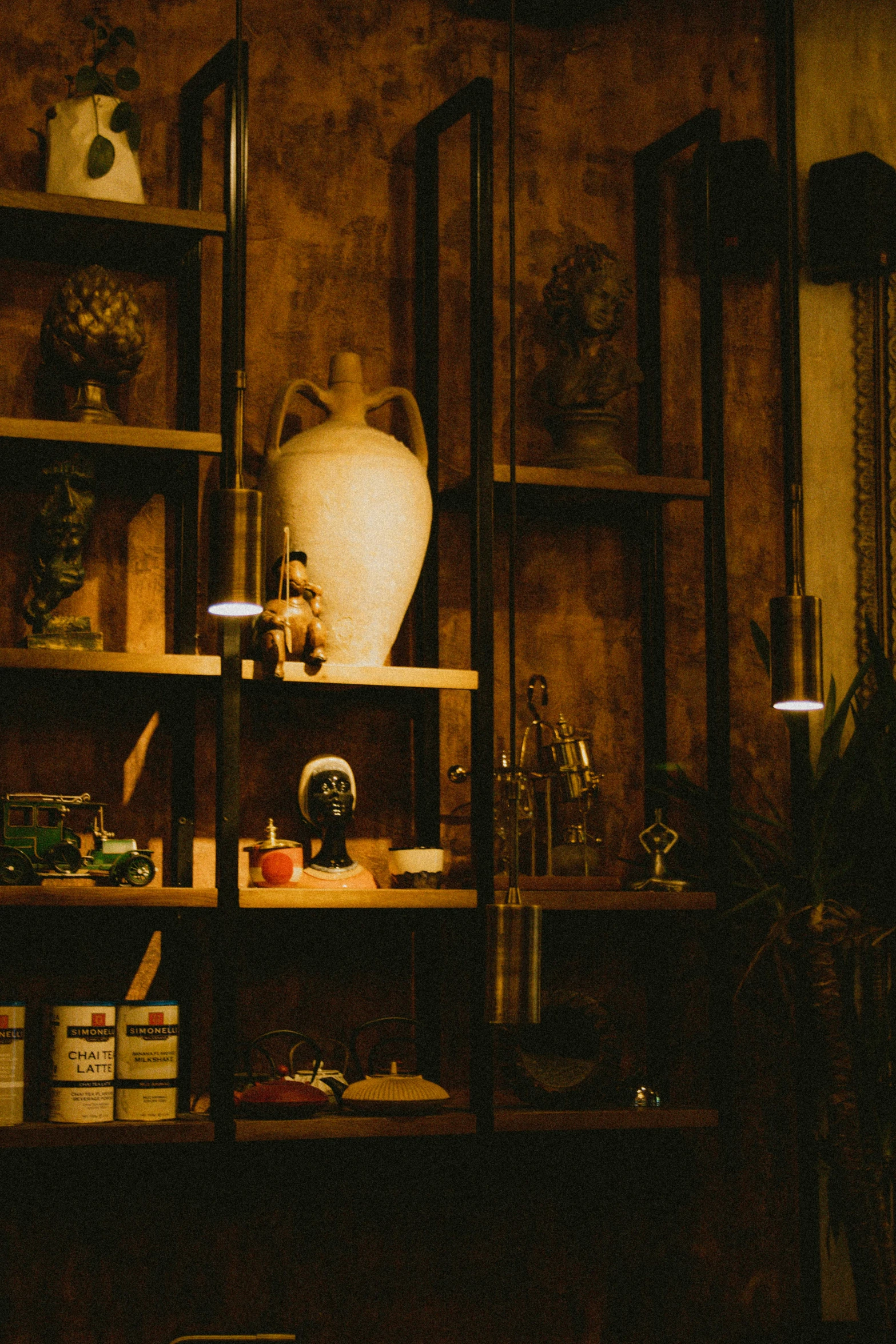 a shelf with bottles and vases is lit by candlelight