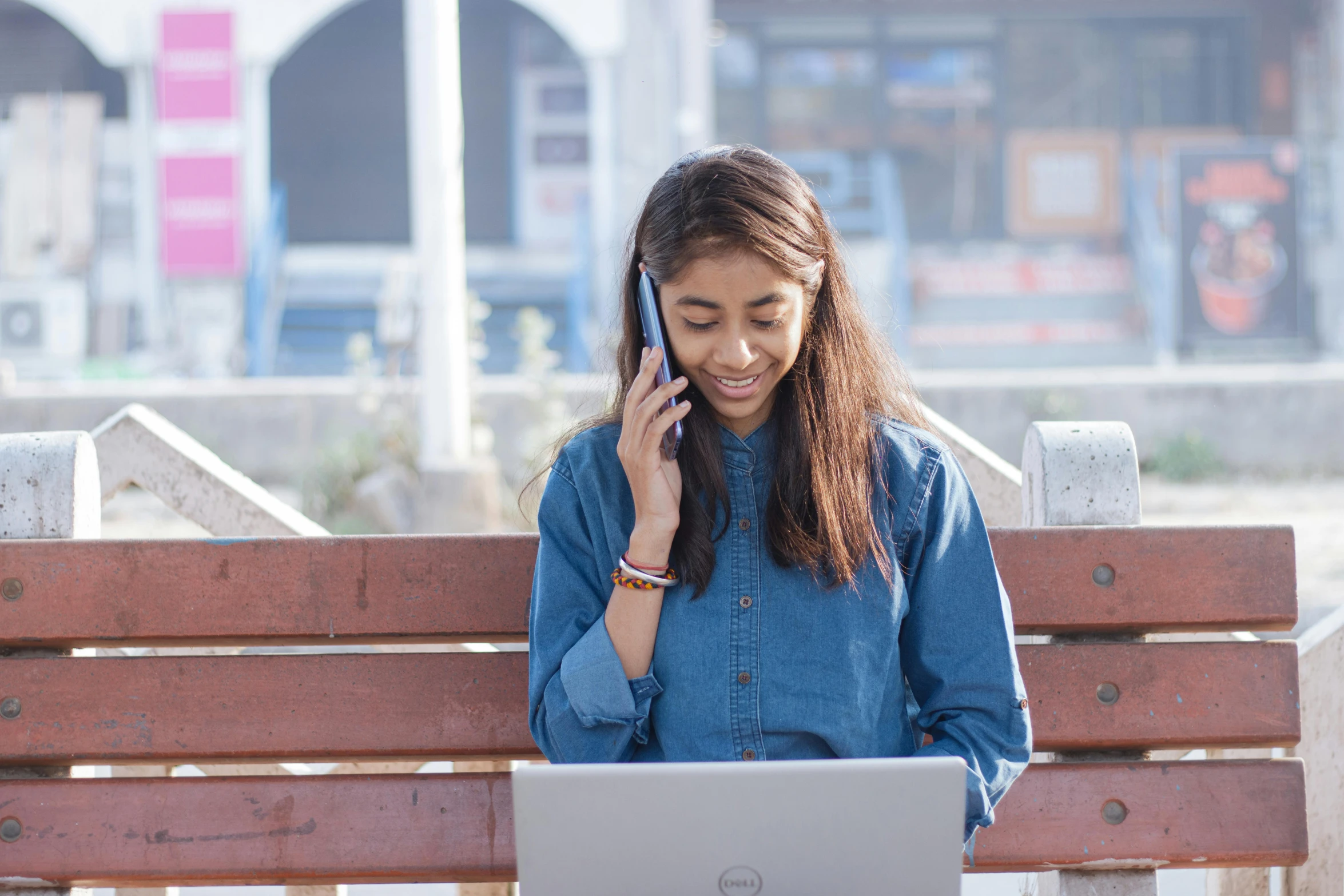 a woman is on her cell phone and sits on a bench