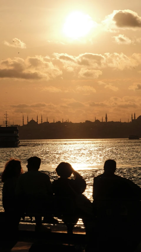 some people sitting near the water with a boat in the distance