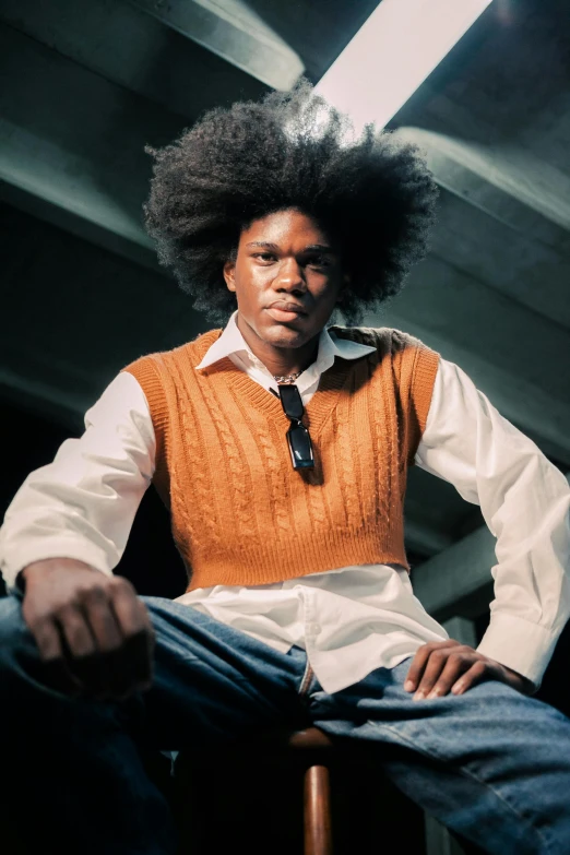 an african american man in a vest and tie sitting in a chair