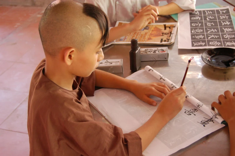 a  sitting at a table with his papers and pencil