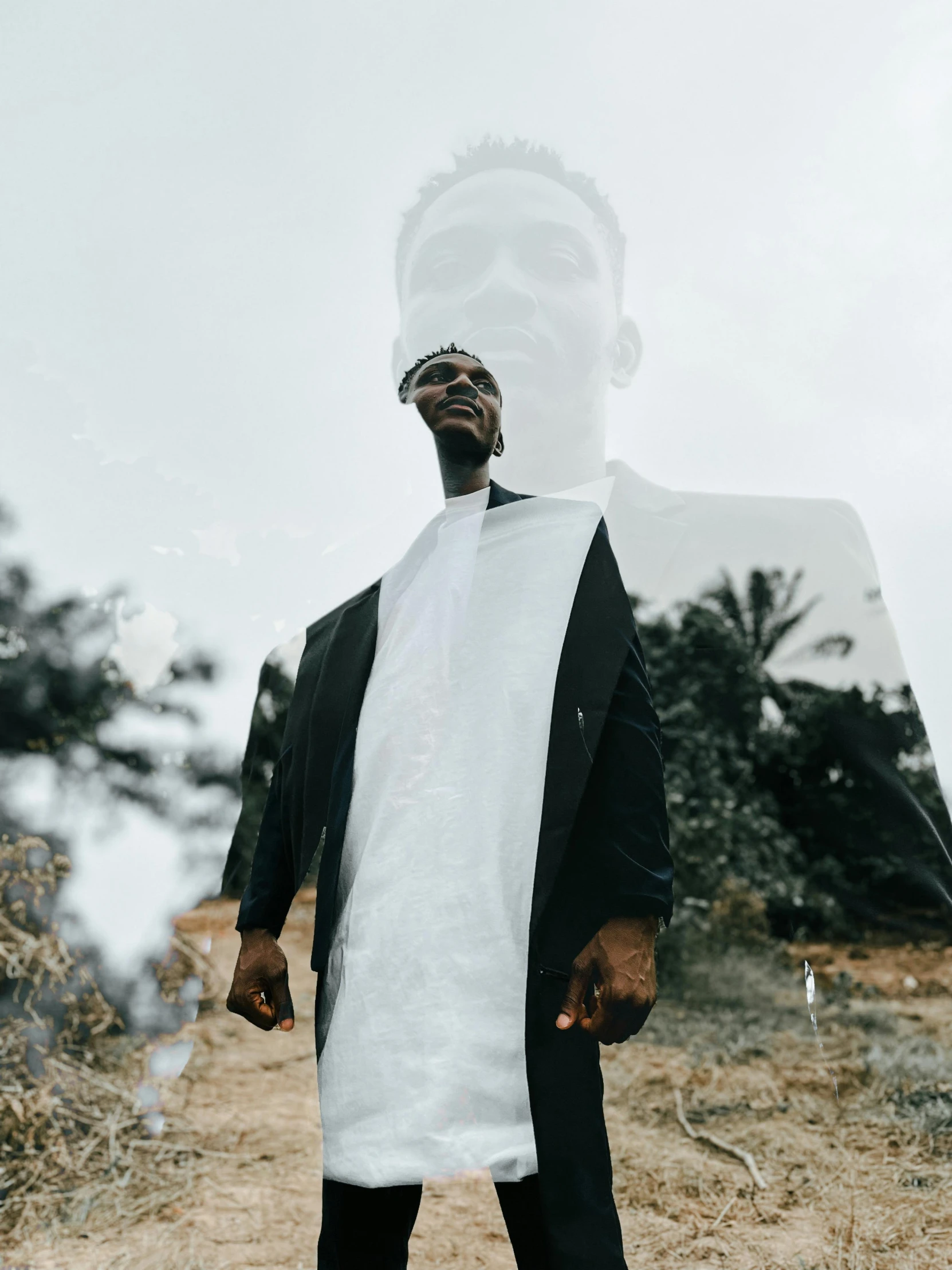 a man is standing in a field with his jacket on