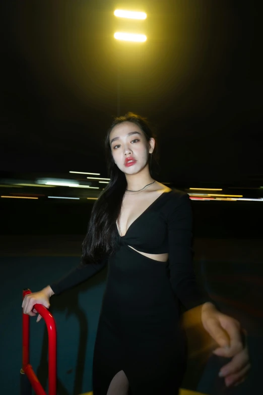 a asian woman in black dress standing outside in the dark