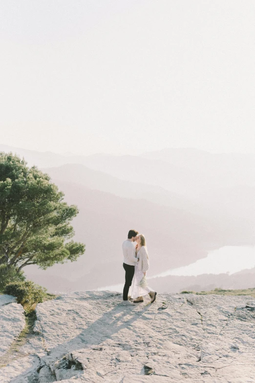 a couple is on top of a mountain with a tree