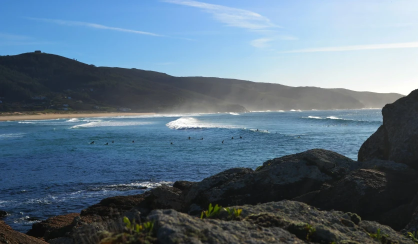 there is a view from a cliff to the ocean and hills