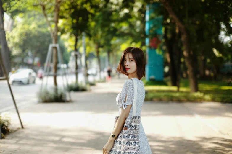 a young woman is walking down the sidewalk with a hand bag