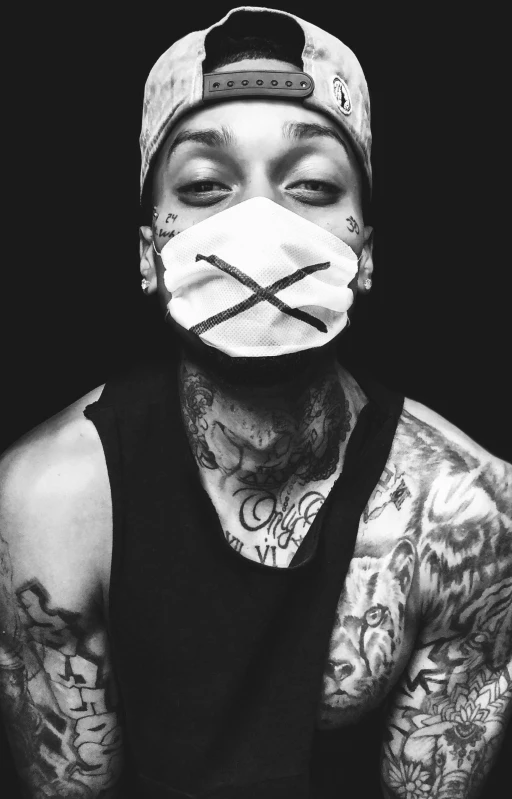 a tattooed man wearing a face mask with a cross pattern