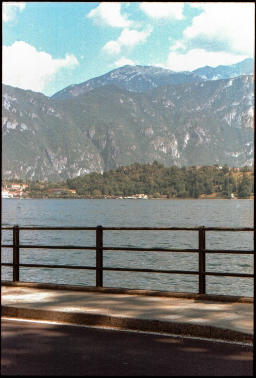 a person sitting at a bench overlooking a lake and mountains
