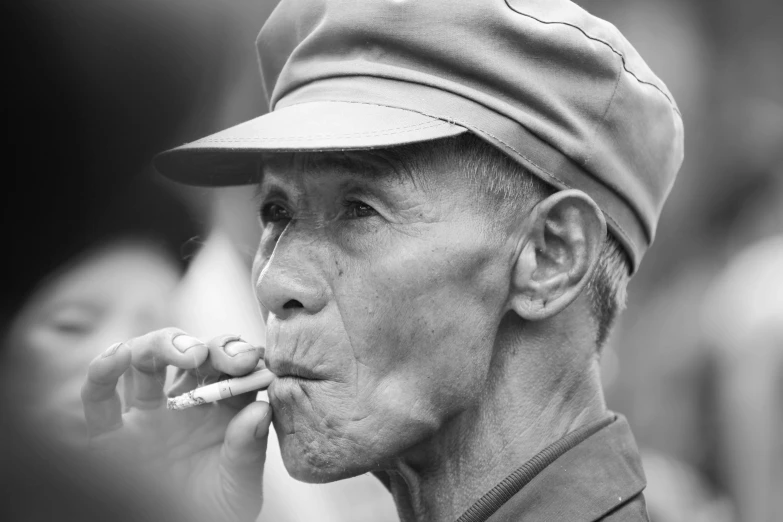 an old man wearing a hat is smoking a cigarette