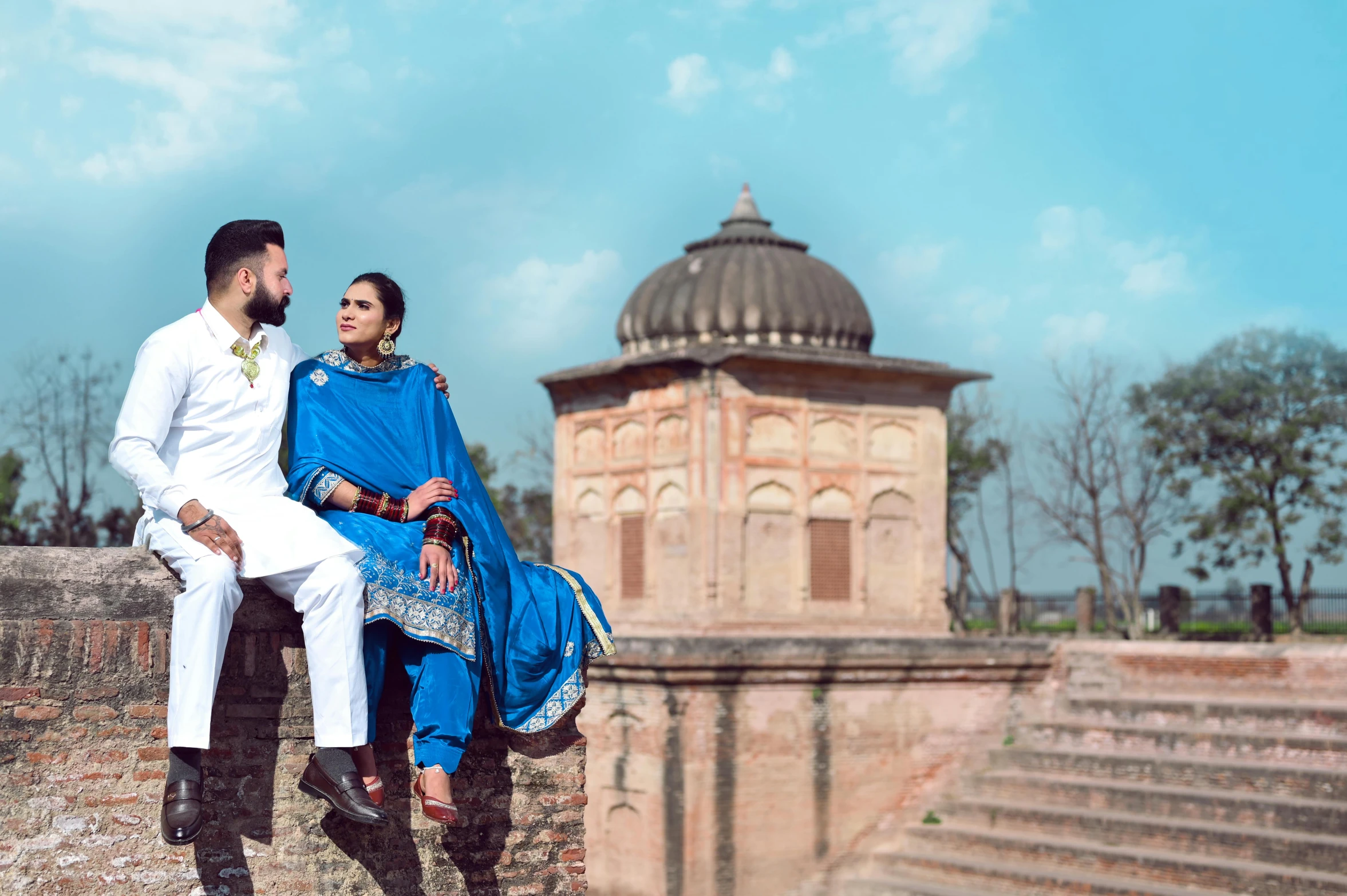 young couple posing in white clothes at a palace