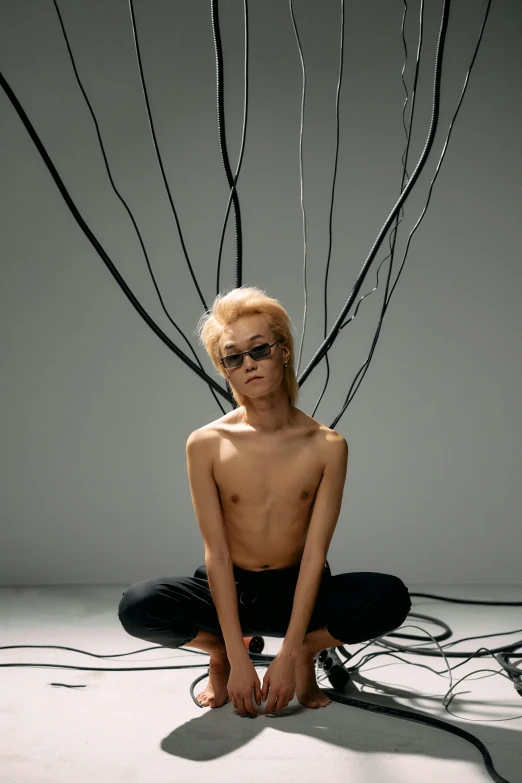 young man with black eyewear sitting in pose with tree nches