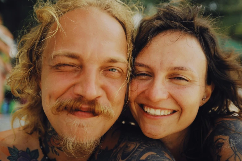 a man with tattoos holding a woman on his shoulder