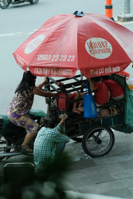 a rickshaw carrying people down the street holding an umbrella