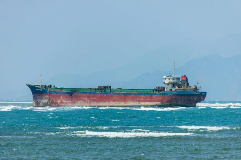 a large ship sailing in the water near mountains