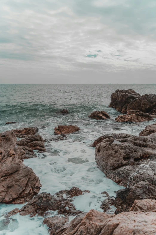 a rocky beach with ocean waves coming in on rocks