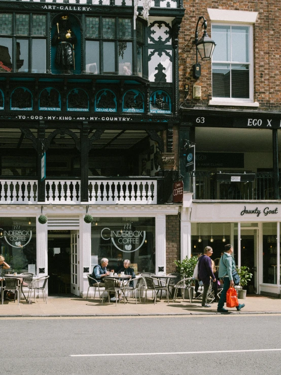 a sidewalk view of many people walking past a restaurant