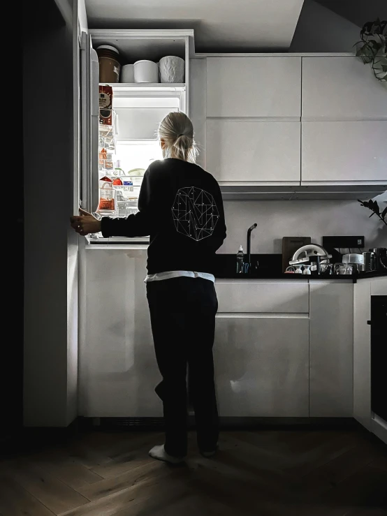 a person in a black sweater is at the kitchen sink