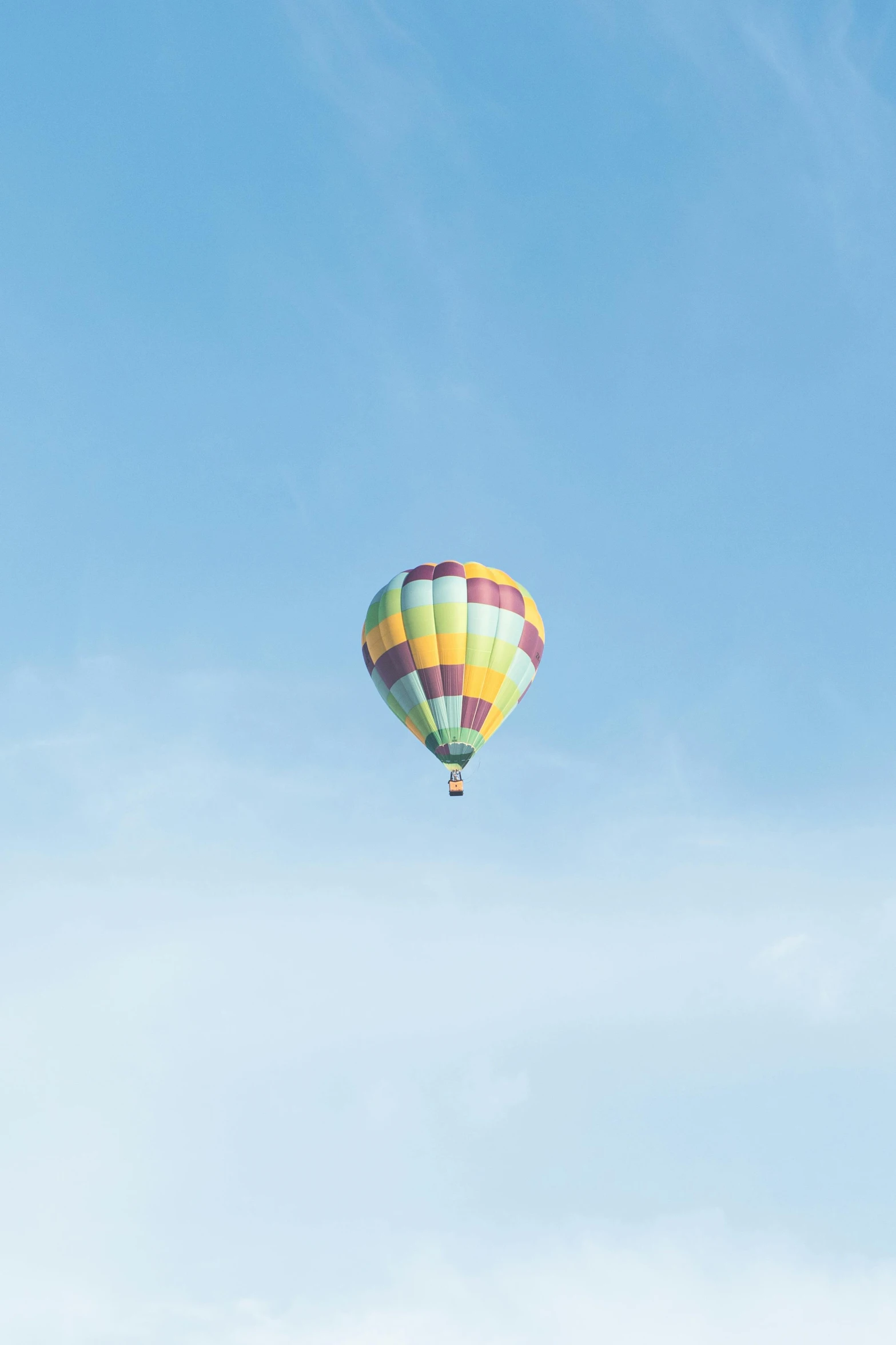 a large multicolored  air balloon flying in a blue sky