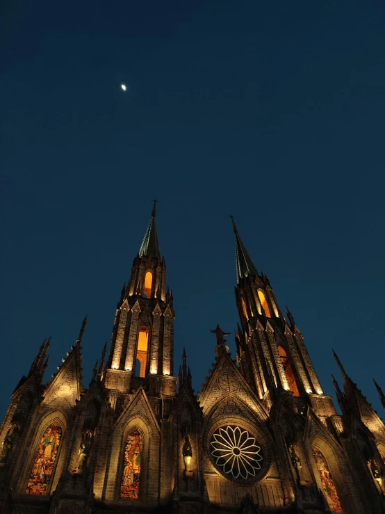 the spires of an illuminated church are lit at night