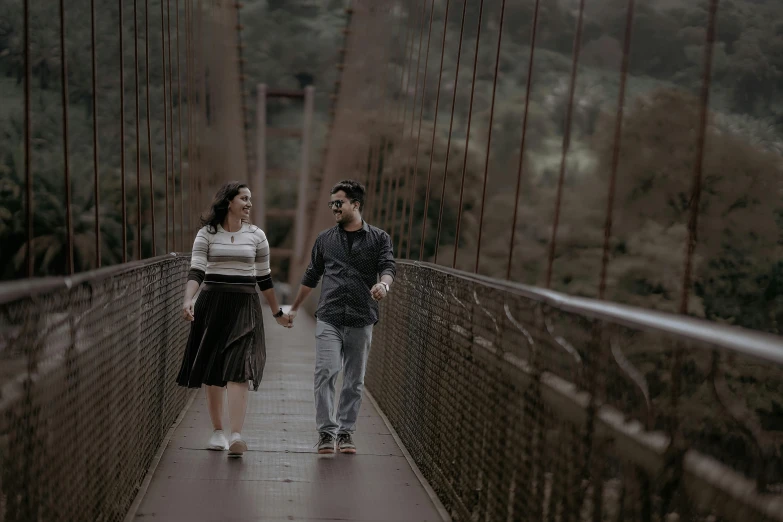 two people walking across a bridge during the day