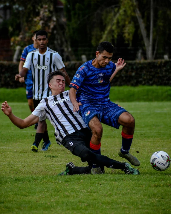 two men playing soccer in a park and one is grabbing the ball