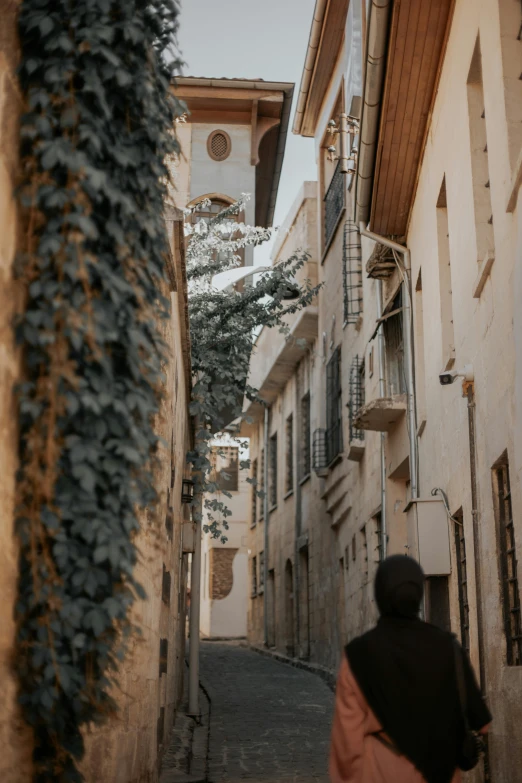 a woman walking through an alley way in a town