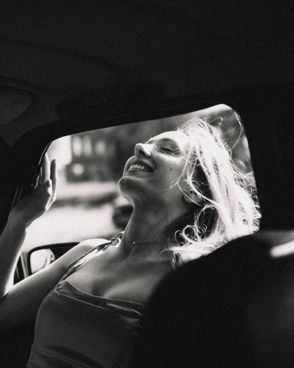 a beautiful young woman sitting in the back seat of a car