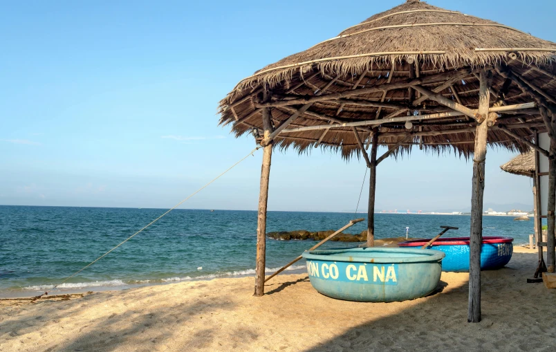 a beach area with a grass roof over an ocean