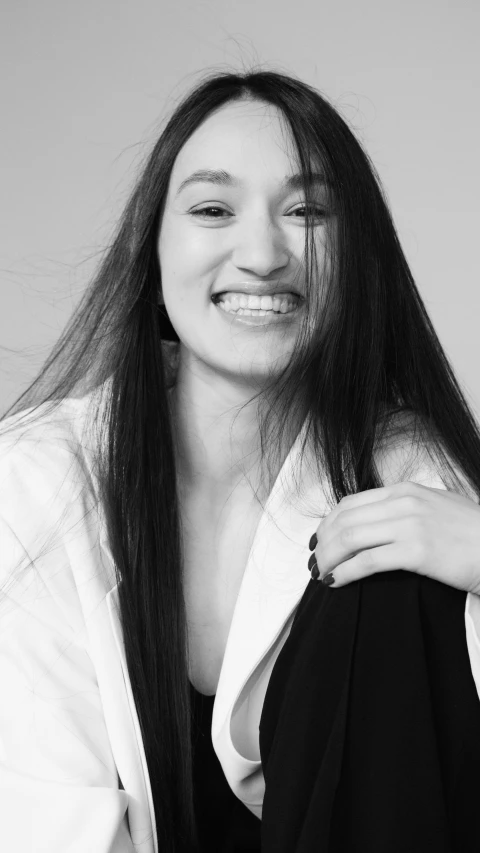 a woman in a white jacket holding her hair in the air