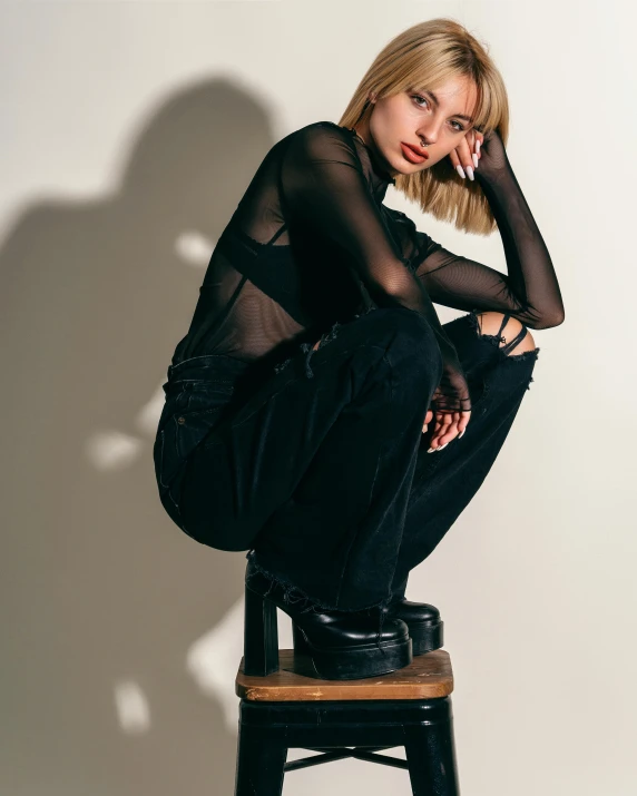 a young woman sits on a stool and poses for the camera